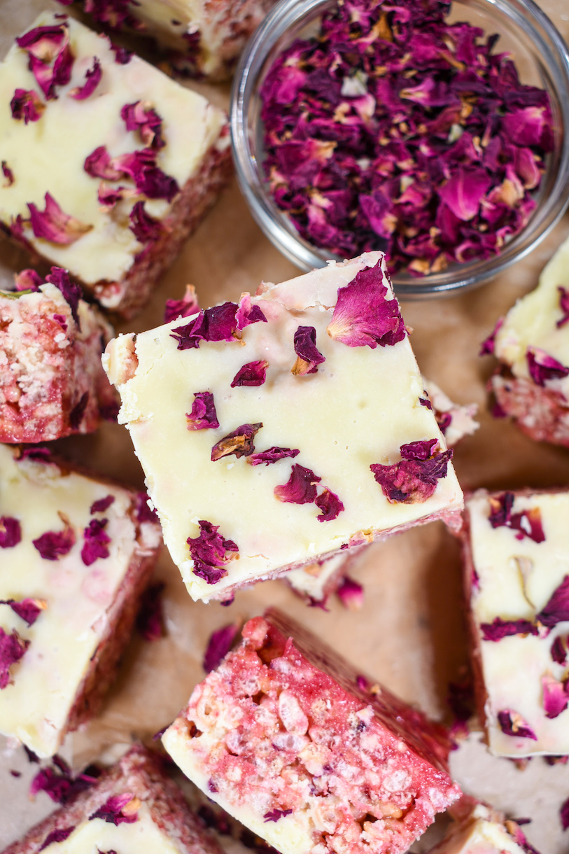 A stack of rose and raspberry rice krispie treats and a bowl of rose petals