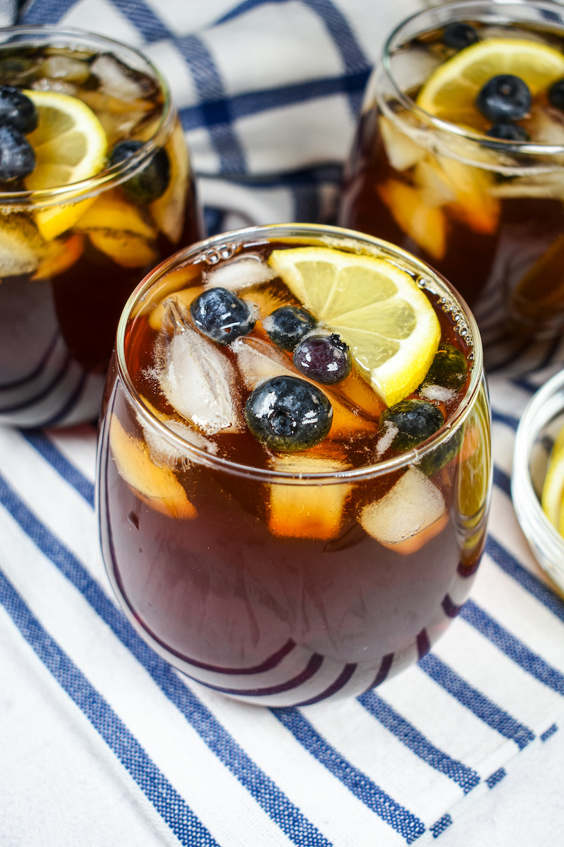 a glass of iced tea with blueberries and lemons