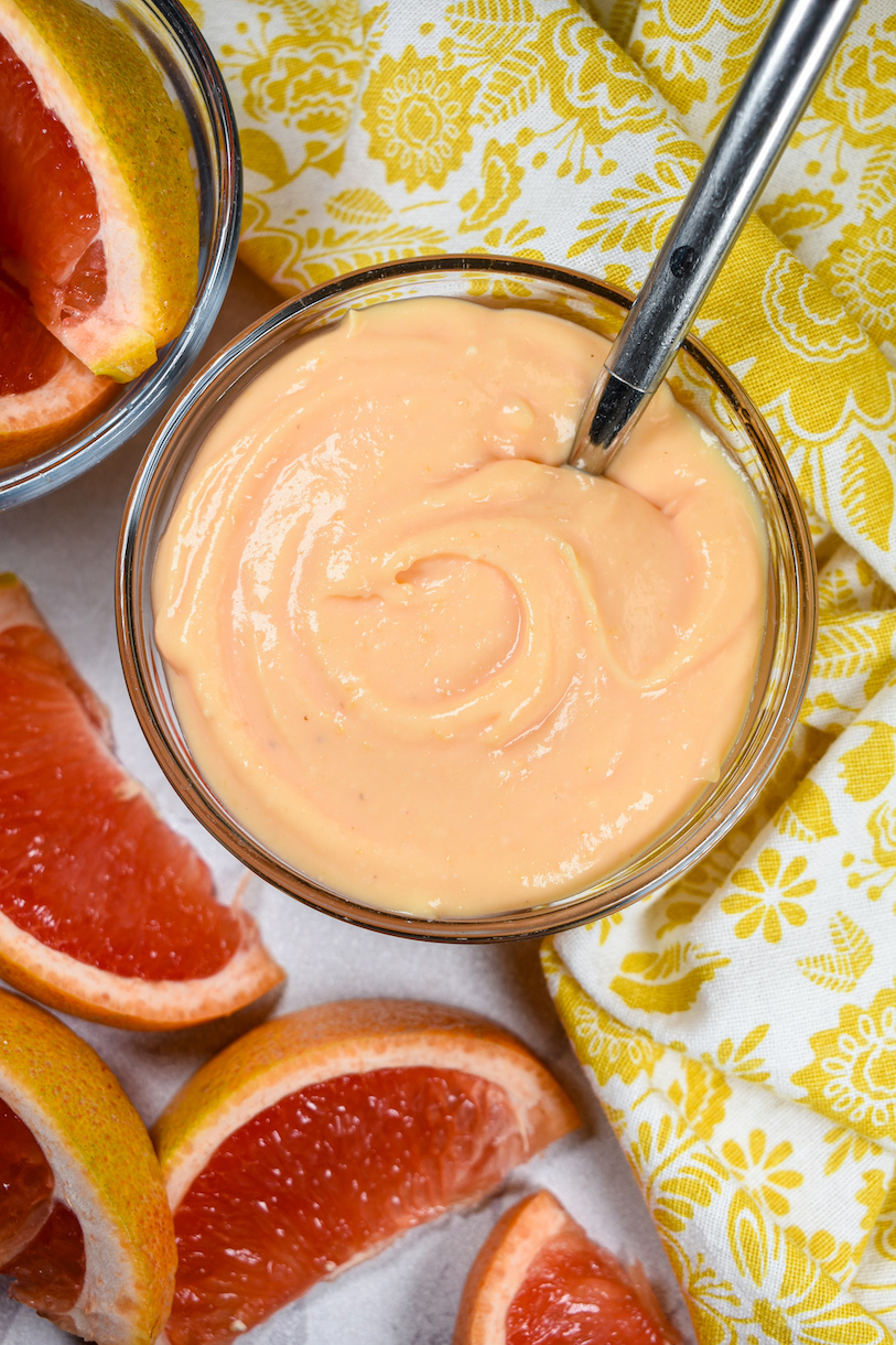 Looking down at a dish of citrus curd with a spoon