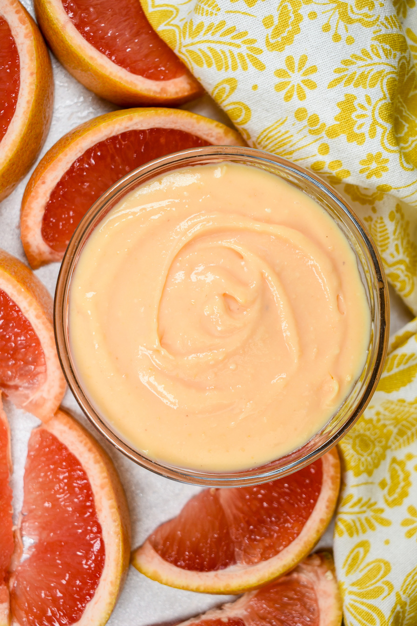 bowl of grapefruit curd surrounded by a yellow towel and wedges of citrus fruit