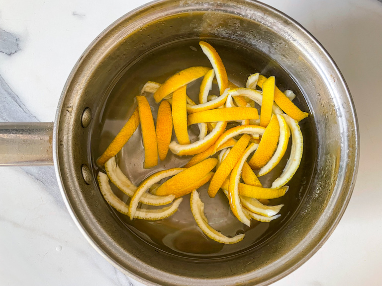 Lemon peel strips in a saucepan of water