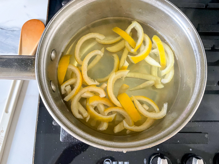 Slices of lemon rind blanching in a saucepan of water