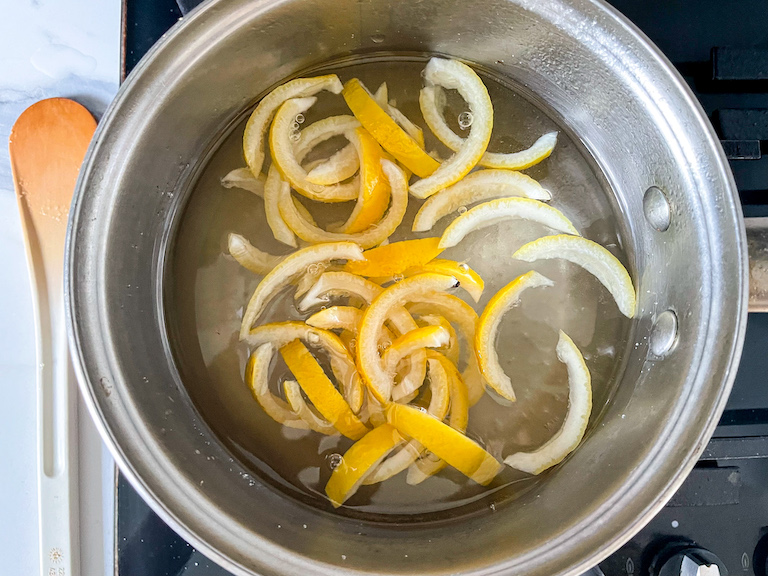 Lemon rind slices in a saucepan of water