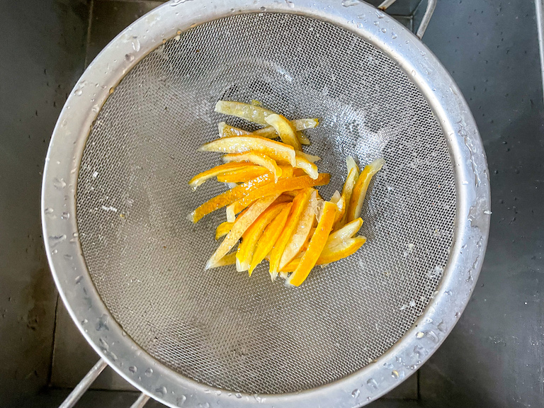 Draining candied lemon peels through a mesh strainer