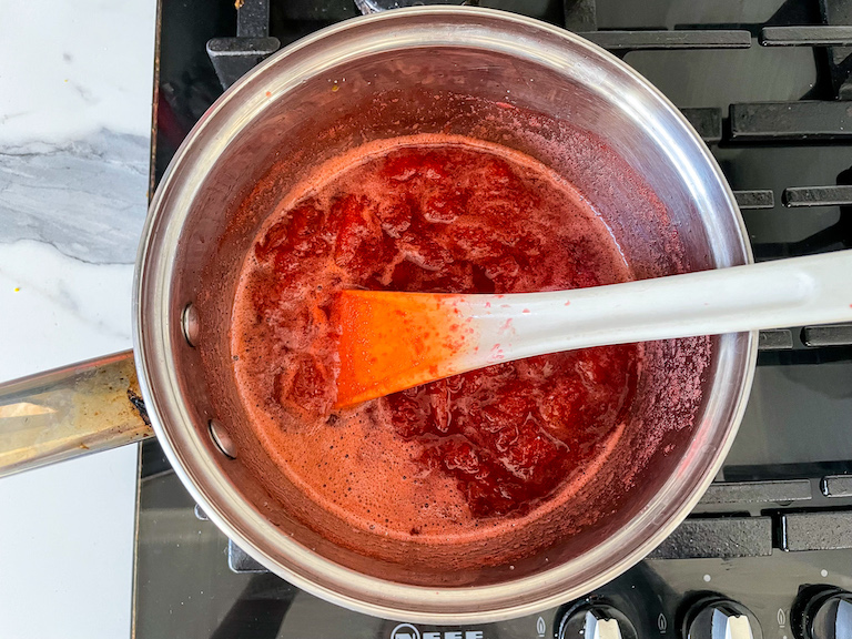Strawberry compote in a saucepan on the stovetop with a spoon