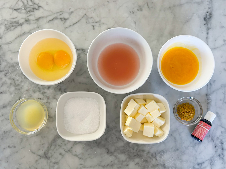 Grapefruit curd ingredients in bowls arranged on a marble surface