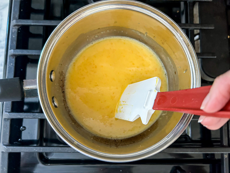 Hand stirring a pan of citrus curd on the stovetop