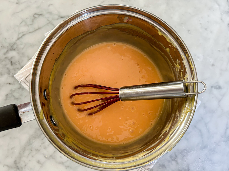 Saucepan of curd with a wire whisk