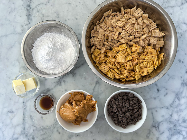 Puppy chow recipe ingredients in bowls on a marble surface