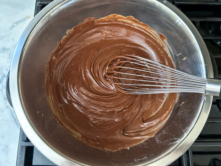 Melted chocolate, peanut butter, and butter in a bowl with a whisk