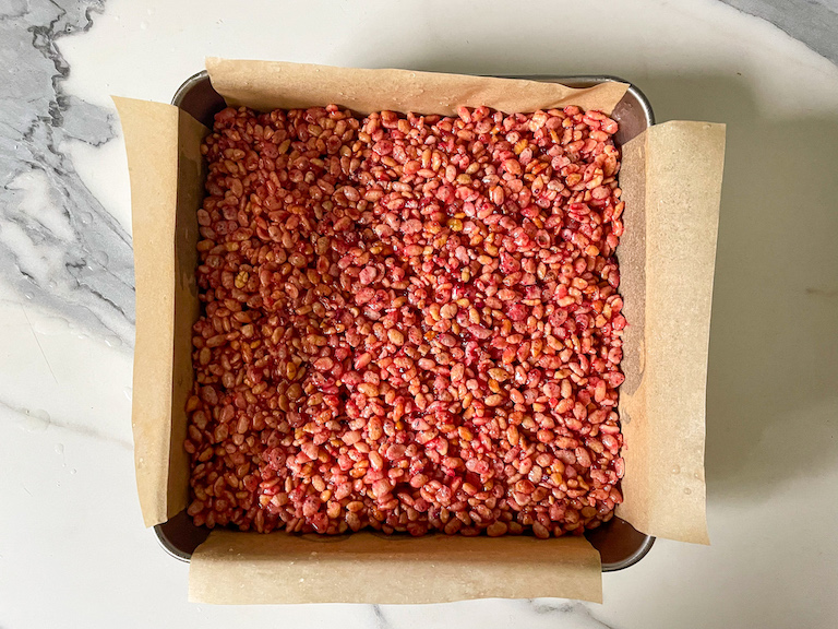 Raspberry rose rice krispie treat mixture pressed into a parchment lined pan