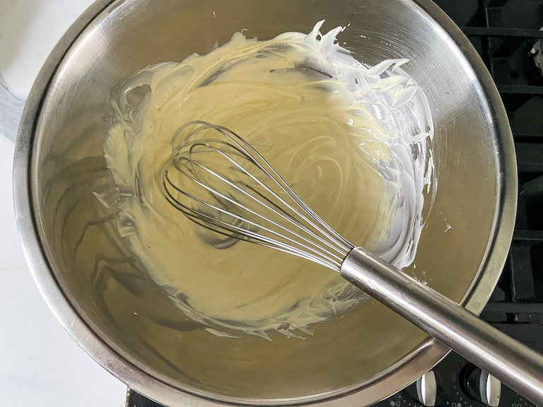 Bowl of melted white chocolate with a whisk
