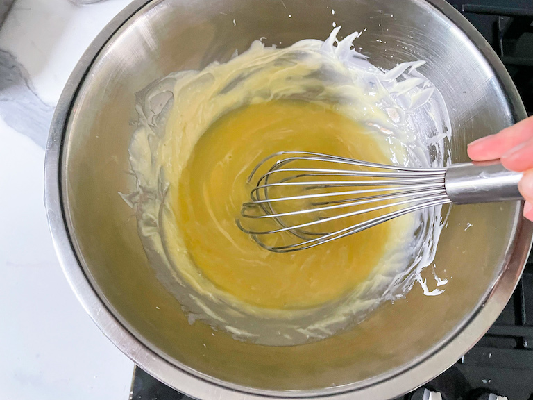 Hand whisking cream into melted white chocolate
