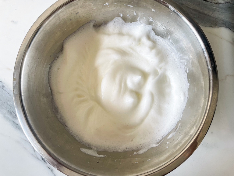 Whipped egg whites in a metal bowl