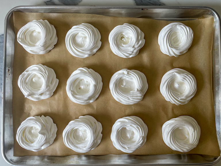 Piped meringue nests on a tray