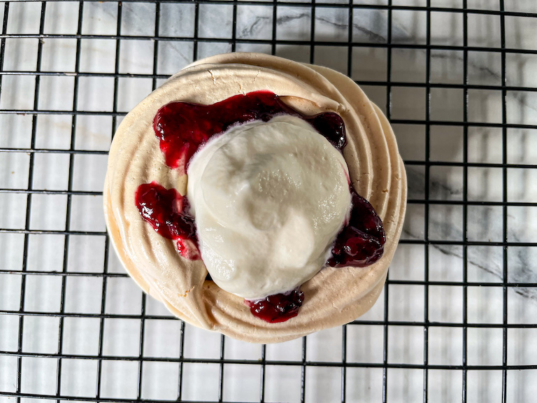 Meringue nest with berry compote and whipped cream on top 
