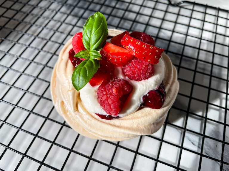 A finished mixed berry pavlova on a wire rack