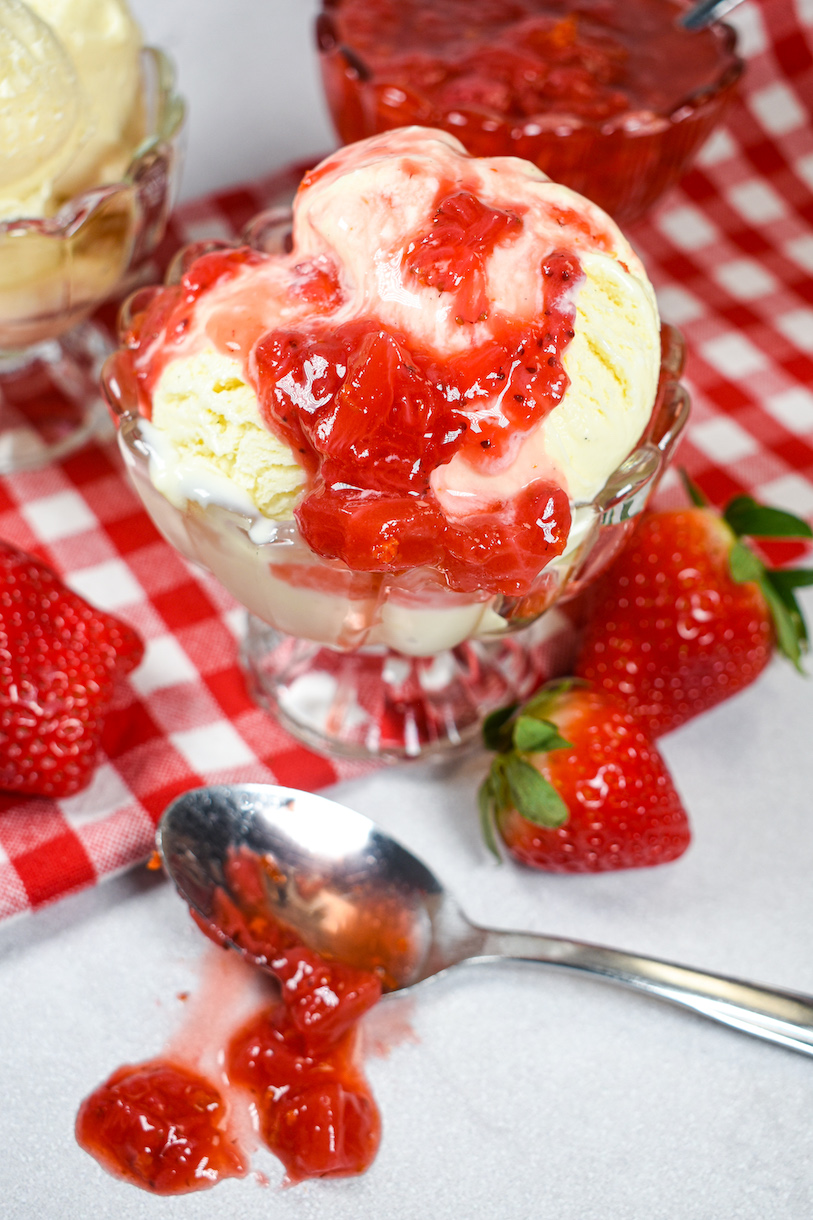 a dish of ice cream with strawberry compote and fresh strawberries