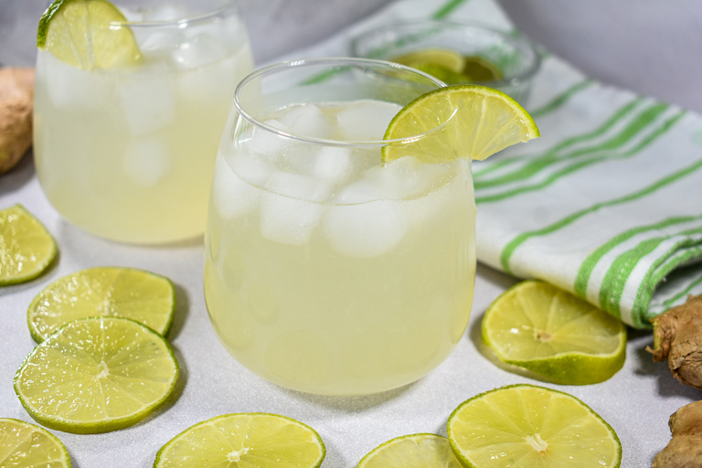 Glasses of limeade surrounded by slices of fresh lime