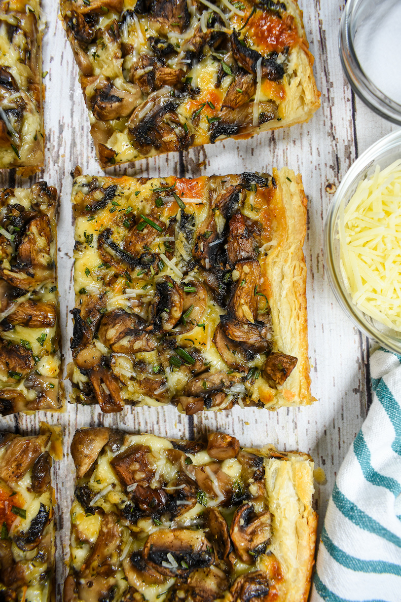 Squares of mushroom tart arranged on a white wood surface