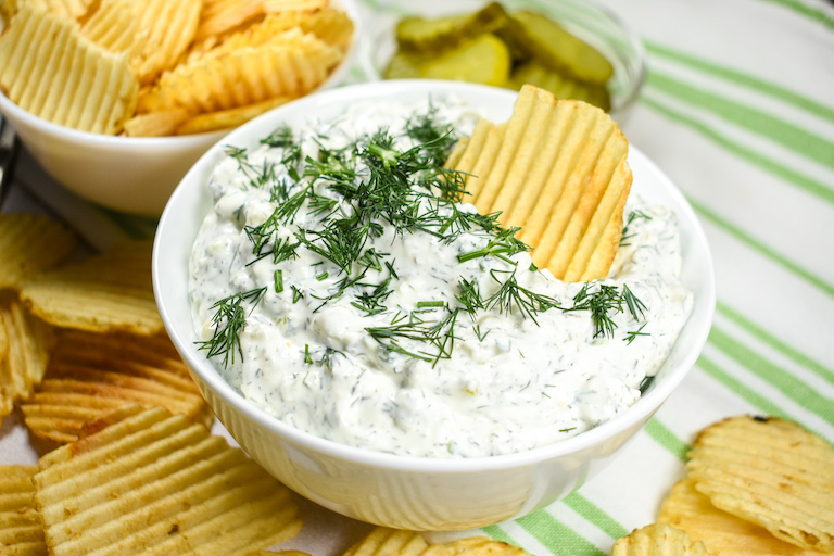 A dish of dill dip with ridged potato chips
