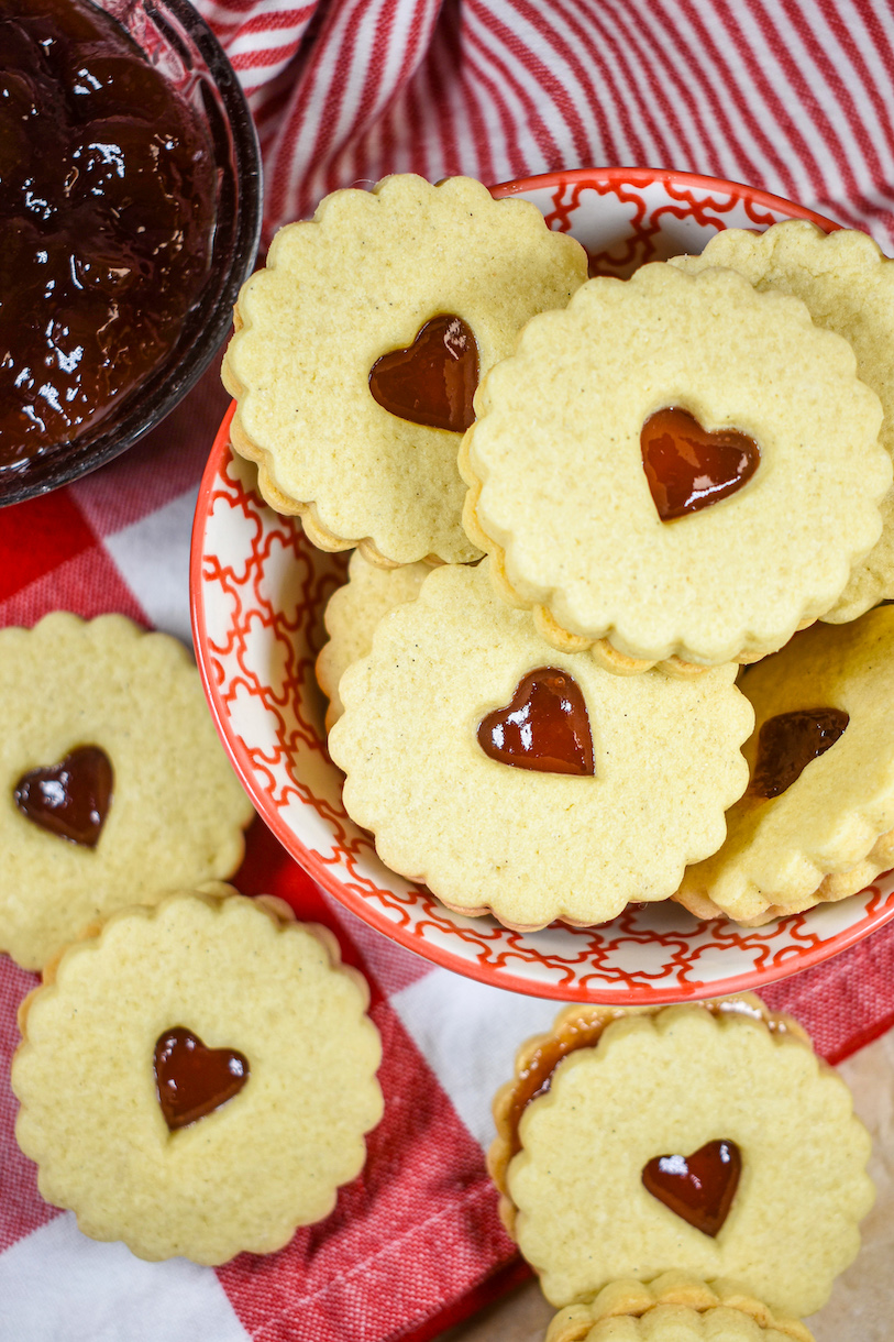 a bowl of jam filled sandwich cookies on a red towel