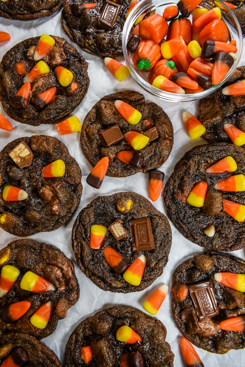 halloween candy cookies and a bowl of candy corn on a white surface