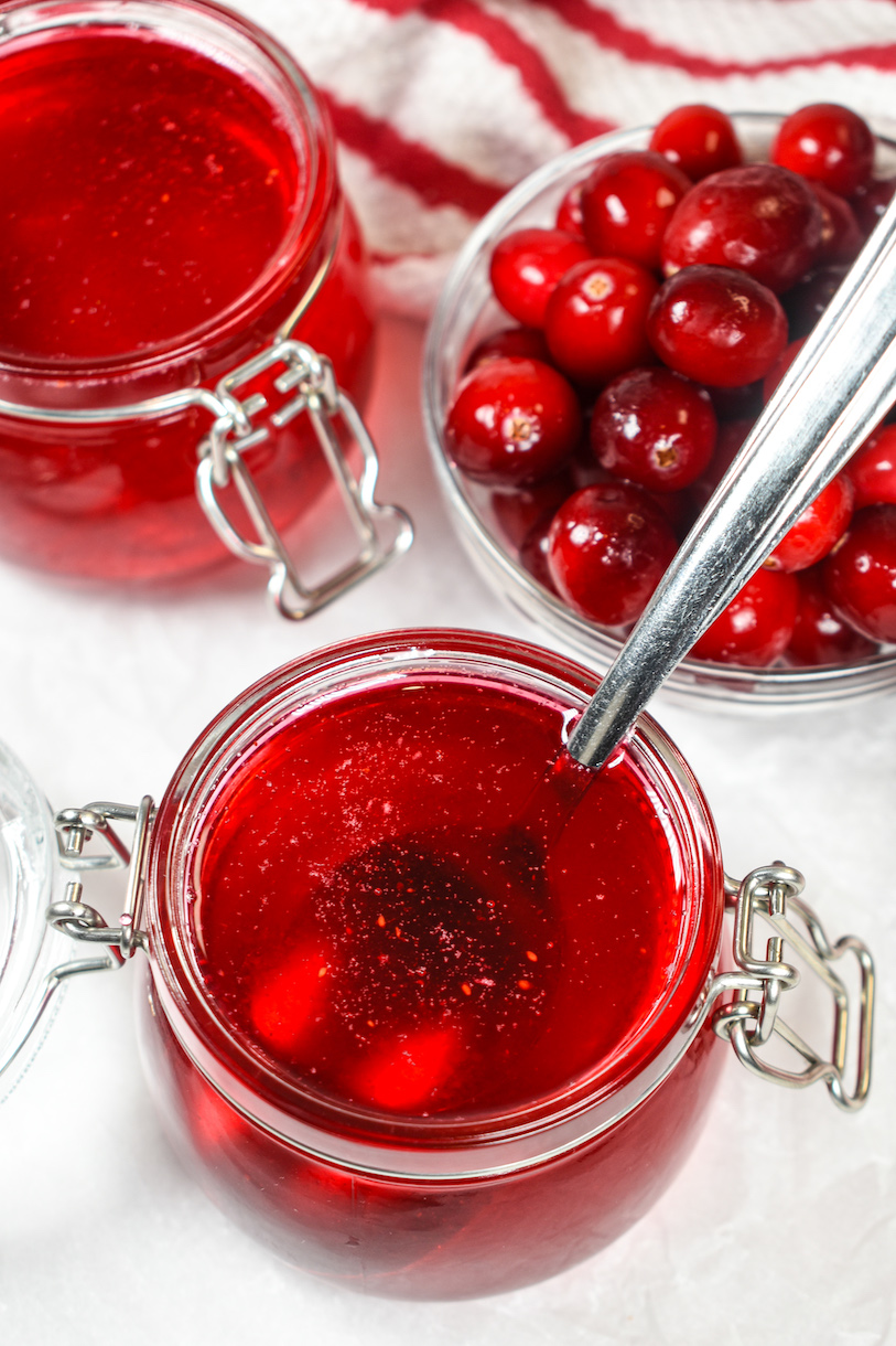 a jar of cranberry syrup and a dish of cranberries