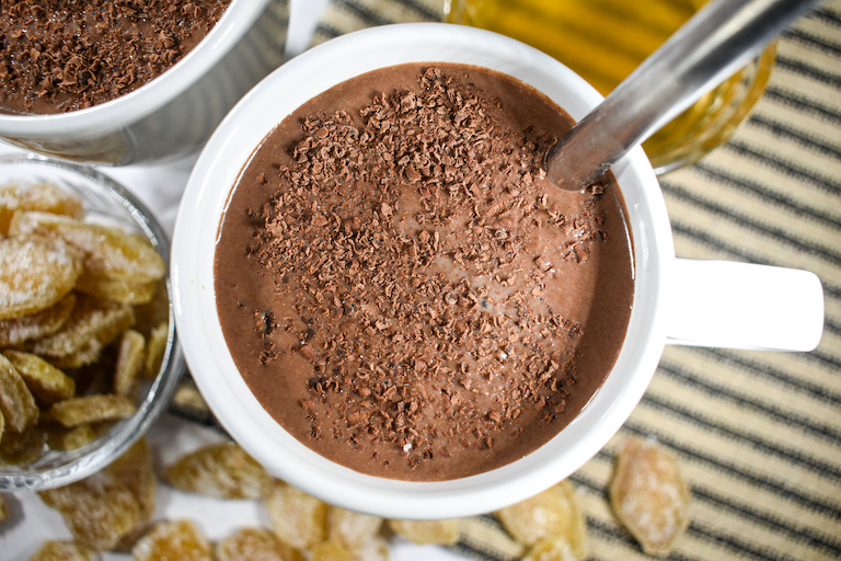 A mug of ginger hot chocolate garnished with shaved chocolate pieces