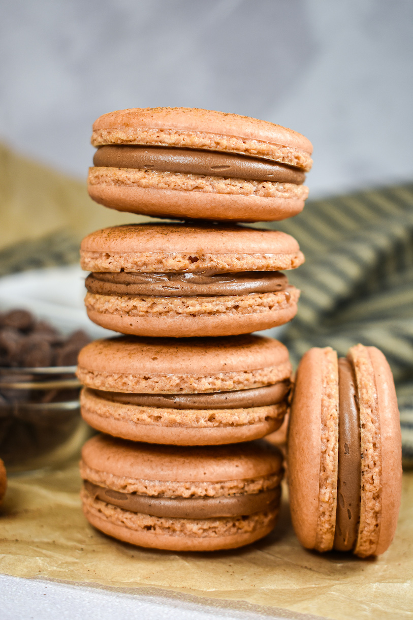 A stack of chai macarons on a sheet of parchment