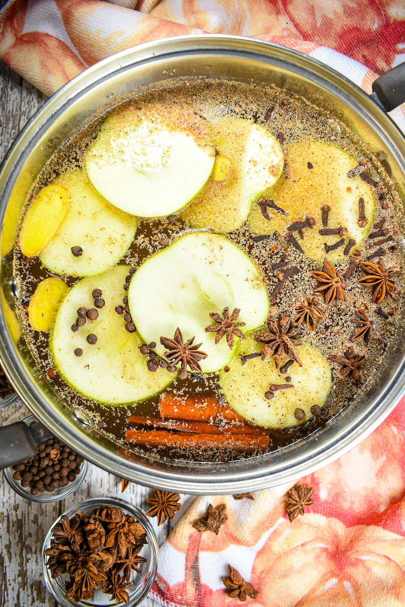 vertical shot of a pumpkin simmer pot with dishes of allspice and star anise