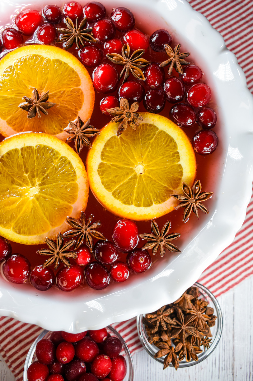 a punch bowl of cranberry punch garnished with cranberries, orange slices, and star anise