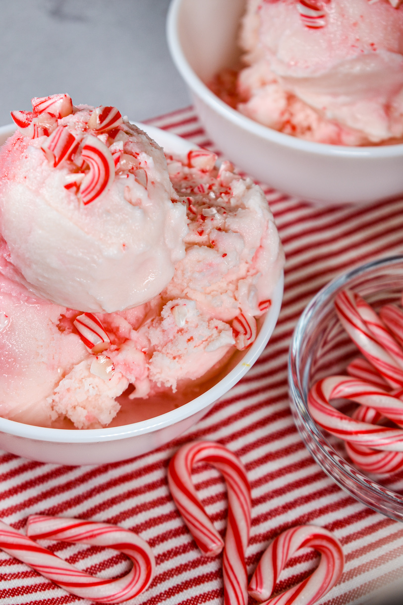 Dish of peppermint stick ice cream on a red and white striped towel with mini candy canes