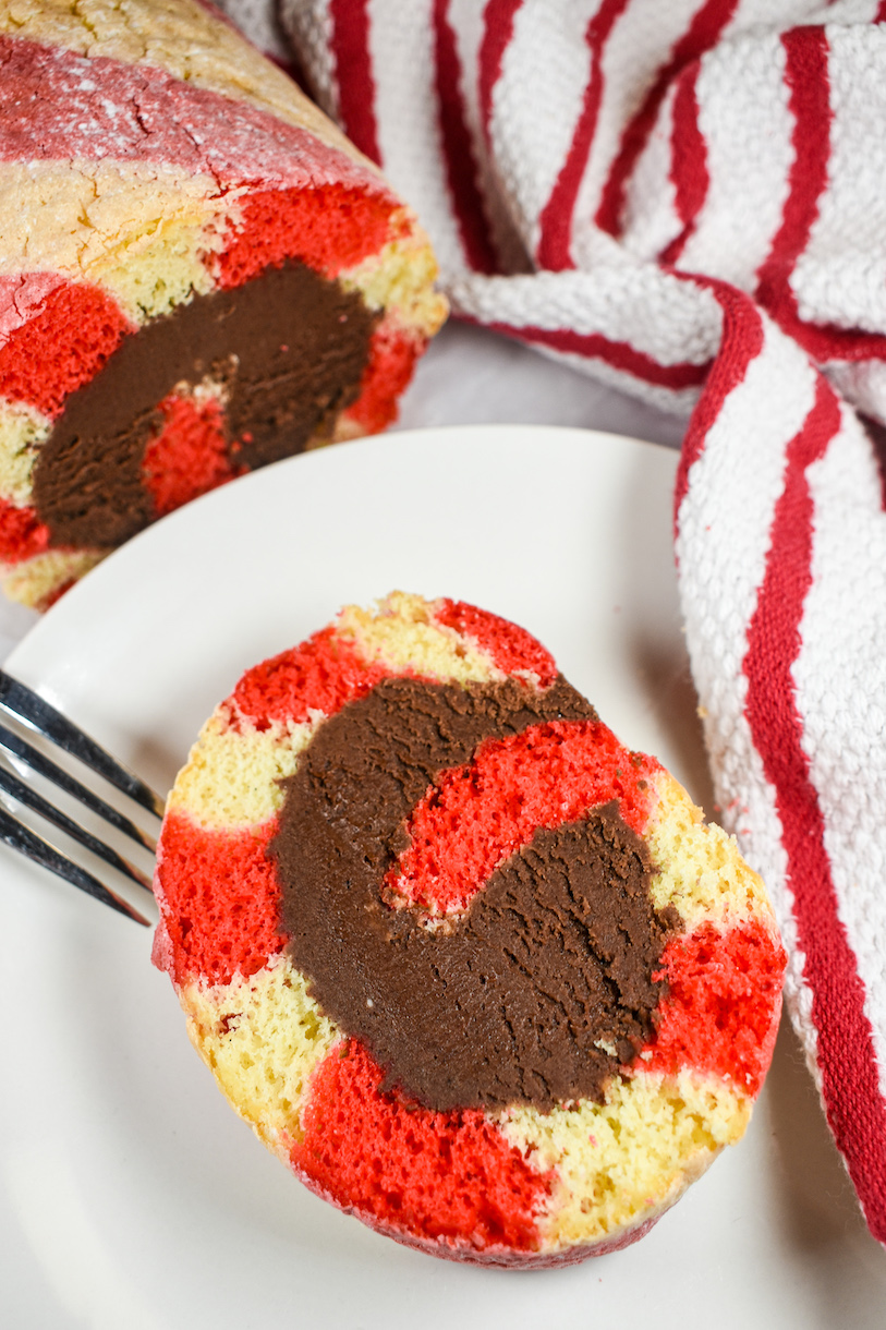 a slice of christmas cake roll on a white plate