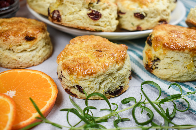 Cranberry scones, orange slices, and rosemary on a white surface