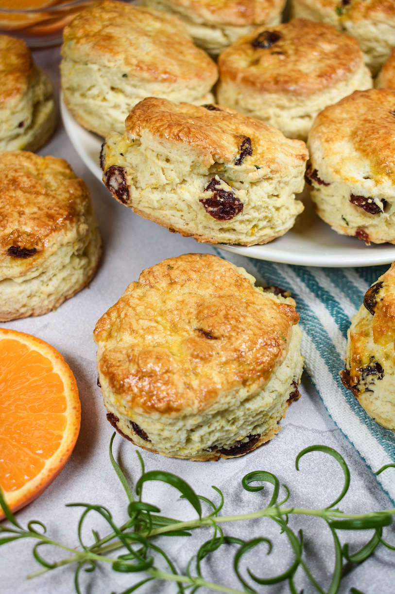 cranberry scones, sprigs of rosemary, and orange slices on a white surface