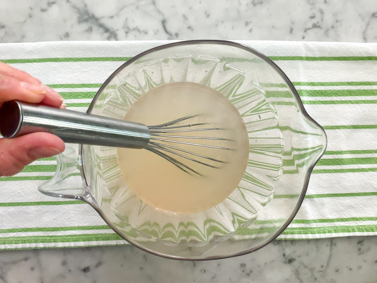 whisking ginger limeade ingredients in a pitcher