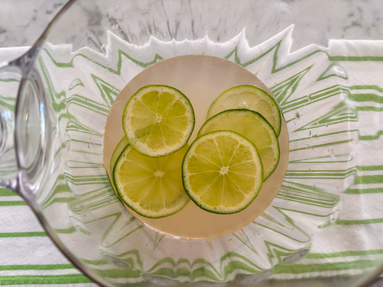 A pitcher of limeade with lime slices floating on top