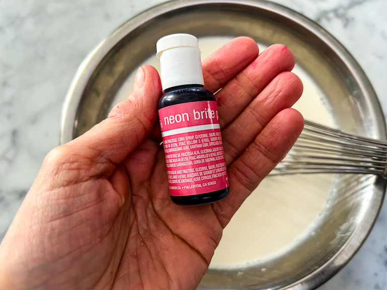 Hand holding a bottle of pink food coloring