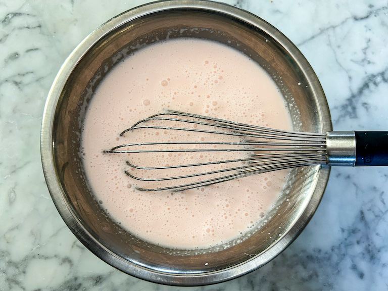 ice cream base in a metal bowl with a whisk