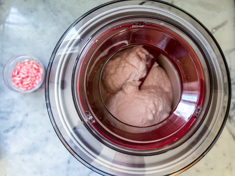 A dish of peppermint candy sitting next to an ice cream maker
