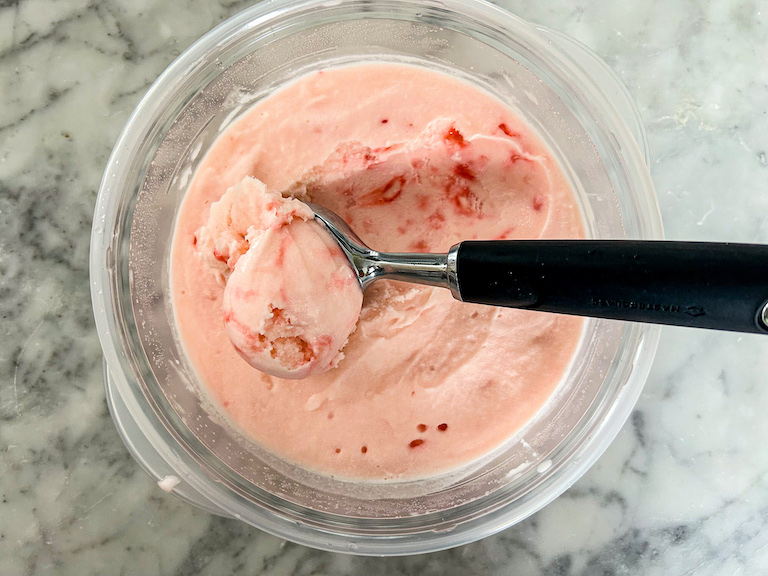 Ice cream scoop in a container of peppermint ice cream