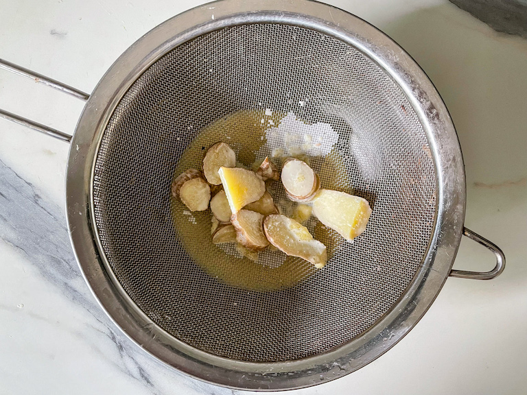 Pieces of ginger in a fine mesh strainer