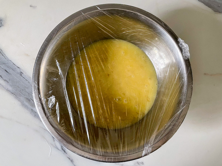 A bowl of white chocolate ginger ganache covered with plastic wrap