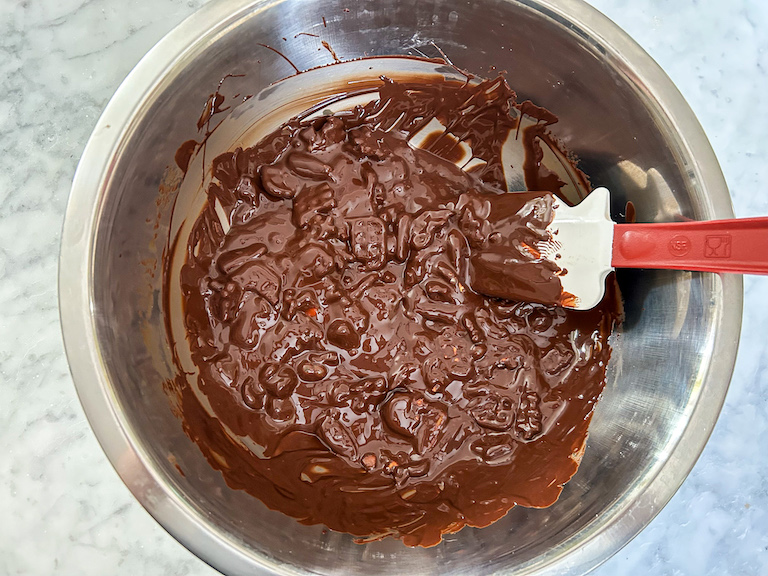A bowl of melted chocolate with a spatula