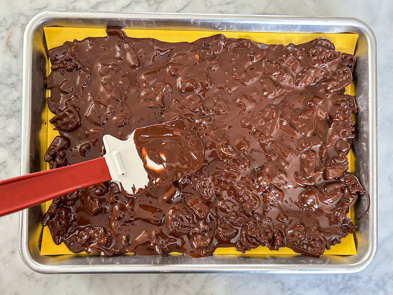 Spatula spreading chocolate across a small tray