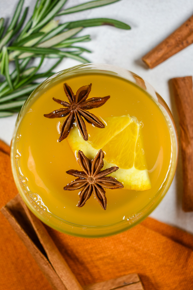 white wine mulled wine in a glass with two star anise and an orange wedge