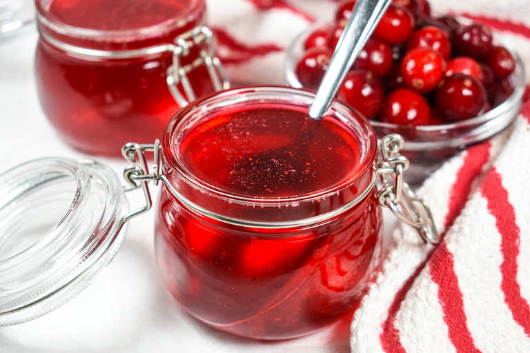 Jars of cranberry syrup and a dish of cranberries