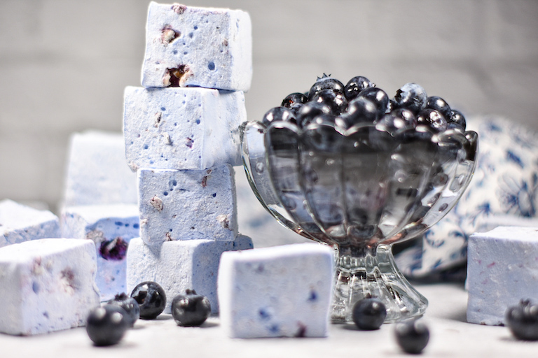 A dish of blueberries next to a stack of homemade blueberry marshmallows