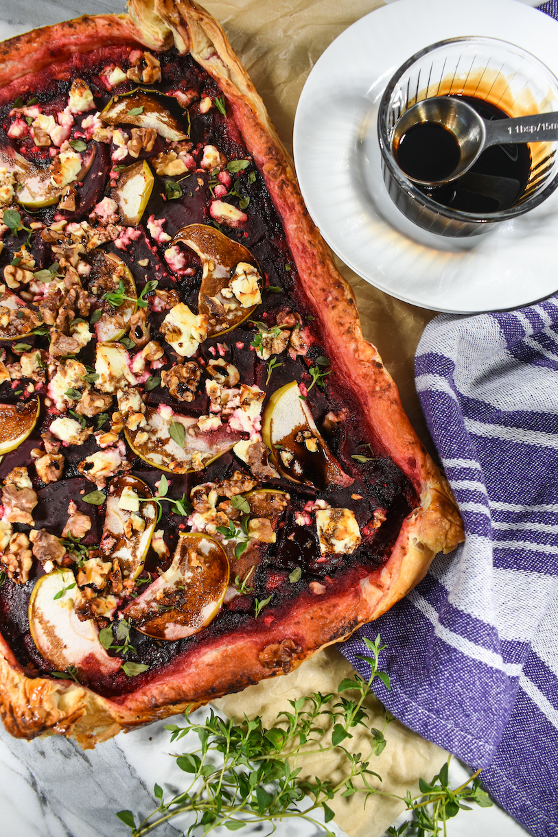 looking down at a beetroot tart on a sheet of parchment with sprigs of thyme